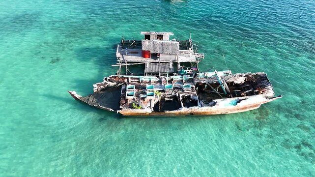 Sunken wooden boat wreckage resting in clear turquoise tropical ocean waters