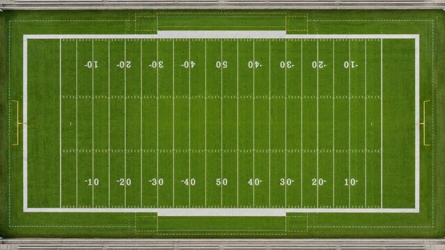 Aerial top-down view of an American football field with marked yard lines, goalposts, green turf, white markings and surrounding bleacher seating