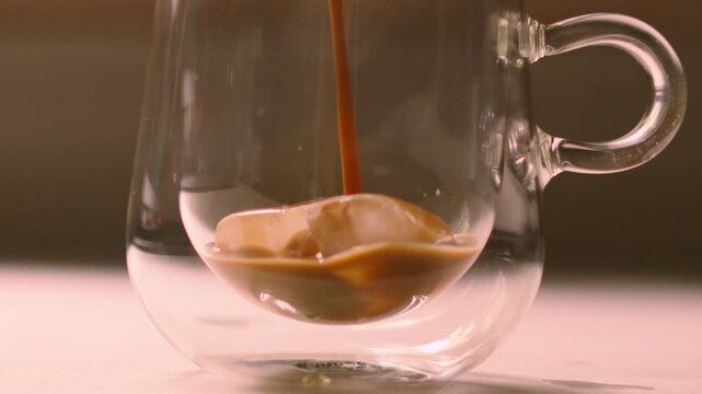 Iced Coffee Pouring on Ice Cubes in Clear Mug in Slow Motion.