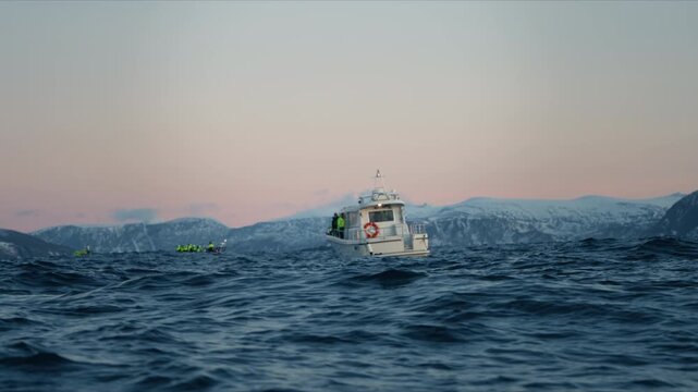 Support boat cruises Arctic fjord beside expedition boats beneath pastel Norway sky