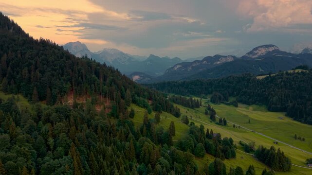 Evening sky, alpine mountain peaks and green fields in Unken Heutal valley, Salzburg Austria aerial.