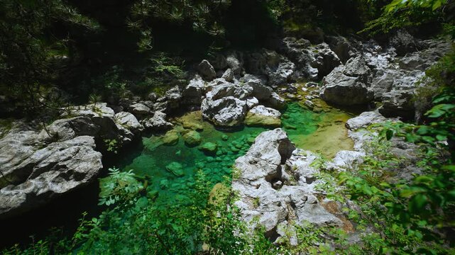 Hidden alpine river rushing over grey limestone with crystal clear green water at Pozze Smeraldine.