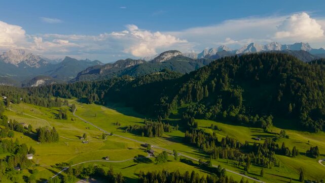 Heutal valley mountain panorama with green meadows, pine forest and dramatic cloud formations. Austria aerial