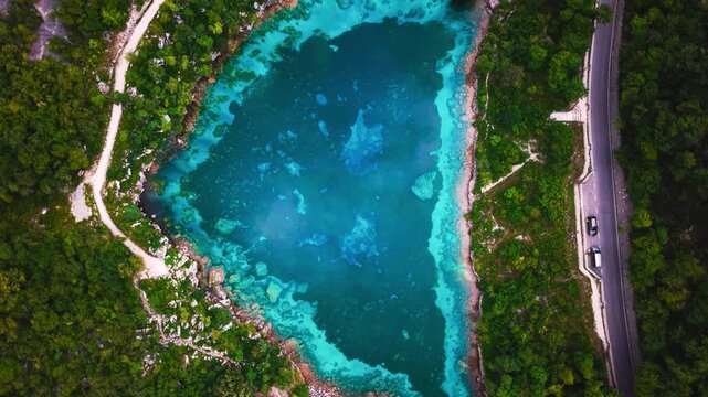 Crystal clear Lago Cornino mountain lake surrounded by turquoise water and trees, Italy. Top down aerial