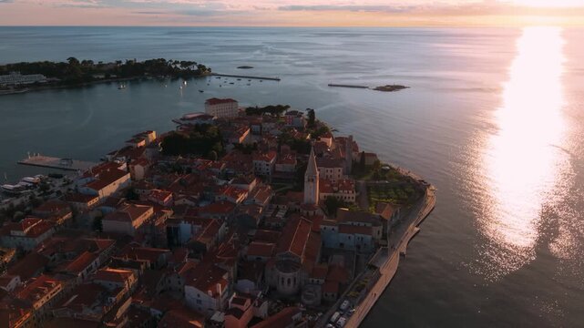 Porec historic center at golden hour with sun reflecting on the Adriatic sea, Istria, Croatia, aerial