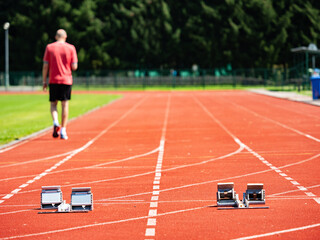 Fototapeta premium Running Track Starting Blocks with Blurred Athlete Outdoors