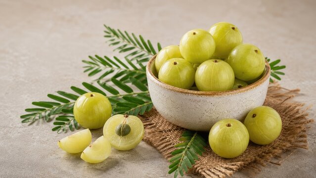 Bowl of fresh green amla (Indian gooseberries) with leaves and sliced pieces on rustic cloth