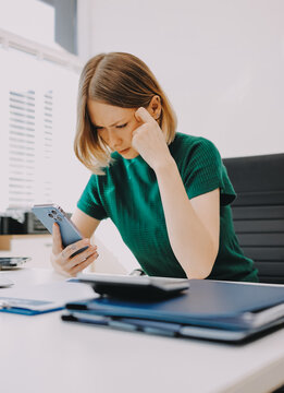 Businesswoman experiencing work related stress and frustration, feeling a headache and burnout from overwhelming tasks while working on her laptop in the office
