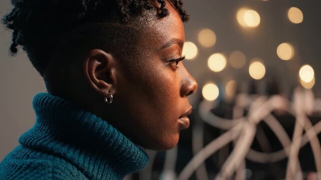 Close-up Profile of a Woman with Natural Hair and Teal Turtleneck Sweater, Soft Lighting and Blurry Background with Bright Bokeh Effects in Artistic Setting