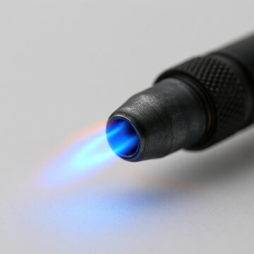Close-up of a powerful butane torch nozzle with a bright blue and orange flame on a neutral background
