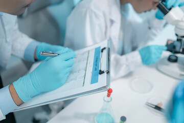 Biomedical scientists perform laboratory experiments using microscopes, laboratory glassware, and biological samples while recording results to support medical research, diagnostics and biotechnology. © PHOTO4U