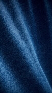Vertical close-up of denim fabric with a clean diagonal fold from light to dark blue, seamless loop texture with copy space for minimal fashion editorial design