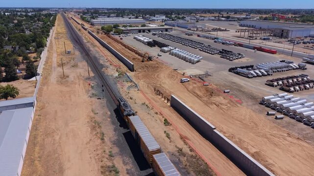 Still Aerial Drone Shot Over Train Track With Train Passing California High Speed Rail Construction Intrusion Barrier Walls and Neighborhoods in Fresno California