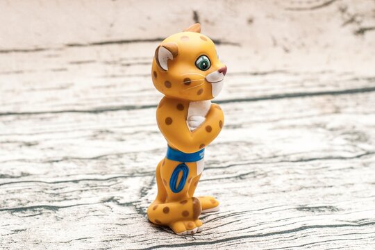 Leopard, mascot of the Sochi 2014 Olympics. A charming yellow cartoon cheetah figure with spots, blue belt, and standing on a textured surface - April 12, 2021, Saint Petersburg, Russia.