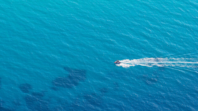 Aerial view of small motorboat cruising in blue sea