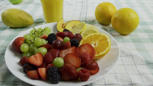 Plate filled with fruit near glass of orange juice - medium tracking shot