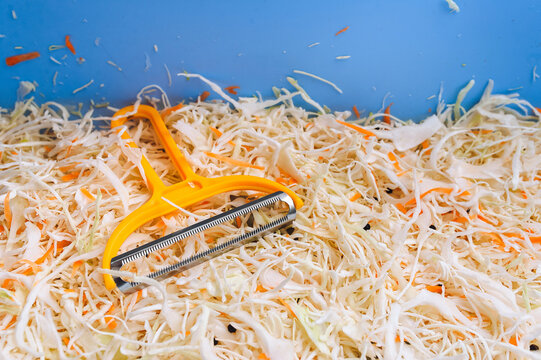 Close-up of a vegetable salad of chopped cabbage and carrots in a blue bowl. Shredding tool, shredder. Homemade sauerkraut. Healthy vegetable food concept.