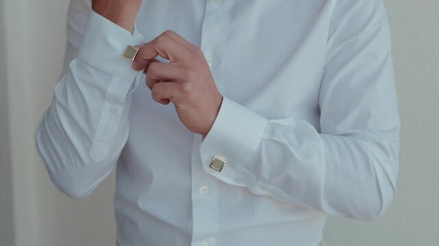 Man in white dress shirt with gold cufflinks moving his hand