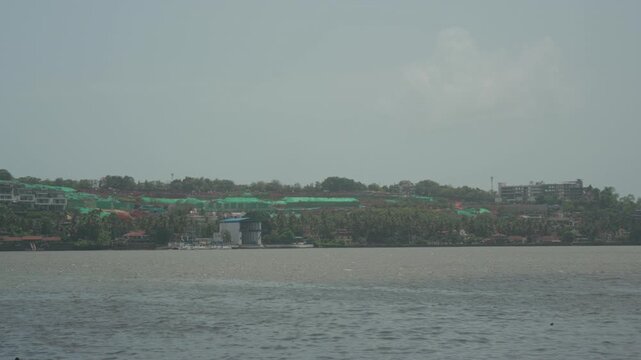 Hill cutting in Nerul village overlooking the Mandovi River, viewed from Panjim, Goa. Scenic riverside landscape highlighting urban development and natural surroundings.
