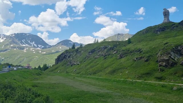 Picturesque view of Simplon Pass, Switzerland, featuring the iconic Stone Eagle Monument on the hill, a WWII symbol of vigilance, surrounded by dramatic alpine landscapes along the route to Italy