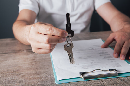 Real estate agent giving keys to customer after signing contract, closeup
