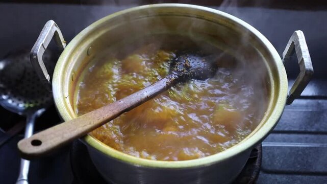 Traditional Indonesian turmeric herbal drink boiling in a pot during the jamu-making process, showcasing natural ingredients and traditional wellness preparation.