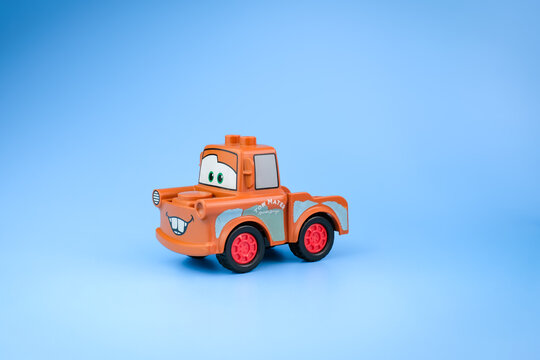 A small Tow Mater character toy from Disney Pixar Cars is displayed in a simple side view with brown bodywork and red wheels on a light blue background on Jul 25, 2026 in Jakarta, Indonesia