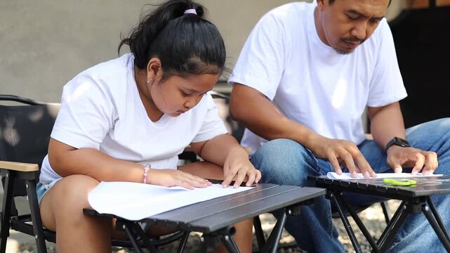 Father and daughter making paper crafts together at home while learning folding techniques and creative skills. Heartwarming family activity that reflects parenting, education, bonding, and Father's D