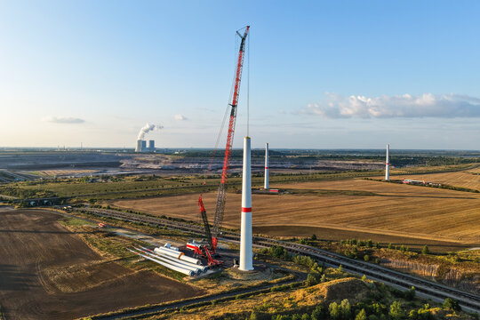 Aerial view of wind turbine construction with a large crane, turbine components, and the Schleenhain lignite open cast mine in the background near Zwenkau, Saxony, Germany.