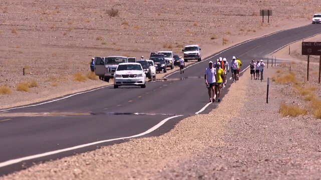 Badwater athletes slowly walking up death Valley hill in the heat