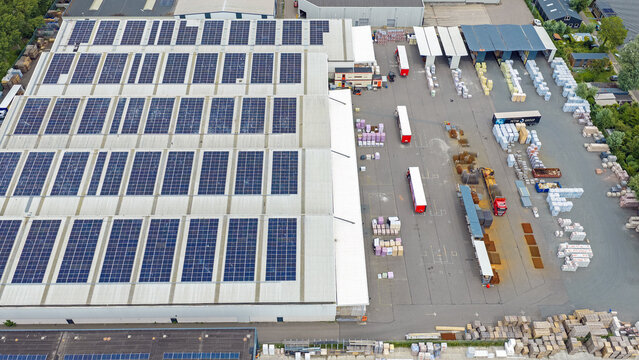 Aerial view of the Boekelermeer industrial facility with a large solar panel roof, trucks in the loading yard, and pallets of goods in Alkmaar, Noord-Holland, Netherlands.
