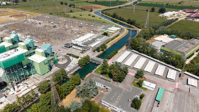 Aerial view of the TTEP Tavazzano thermal power plant and TERNA electrical substation, with industrial buildings, power lines, and a canal in Tavazzano con Villavesco, Lombardy, Italy.