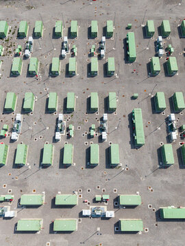 Aerial view of a Battery Energy Storage System installation with rows of green battery containers and electrical infrastructure on a gravel site in Tavazzano con Villavesco, Lombardy, Italy.