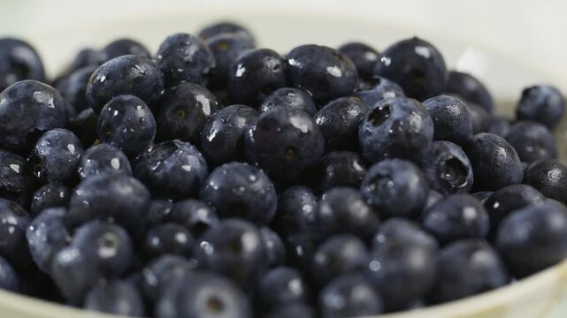 Soaked, fresh blueberries in bowl - slow closeup, tracking shot