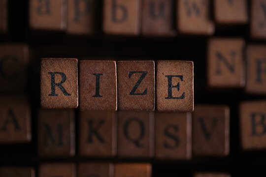 Word RIZE spelled out with dark vintage wooden letterpress stamps in close up overhead view.
