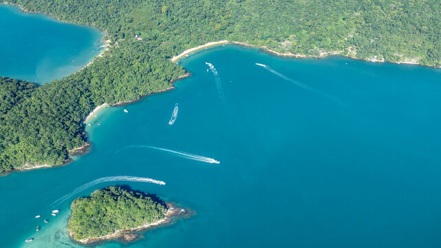 Aerial view of Lagoa Azul, also known as Blue Lagoon, featuring turquoise waters, lush green islands, and boats leaving wakes in Angra dos Reis, Rio de Janeiro, Brazil.