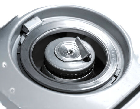 Close up view of a metallic gas stove burner nozzle with a control lever