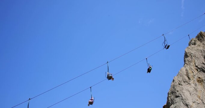 Slow motion footage of the Needles Chairlift at Alum Bay on the Isle of Wight England showing visitors travelling above the famous white chalk cliffs against a clear blue sky on a sunny summer day