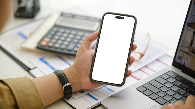Close up of a professional multitasking with mobile phone and laptop in a bright workspace, ideal for business, finance, and technology concepts.