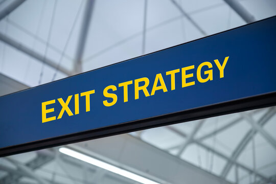 Exit strategy sign with yellow text hanging under glass roof
