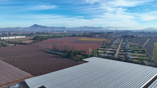 Aerial view of agricultural fields and greenhouses with mountains in the background in Santiago, Santiago Metropolitan, Chile.
