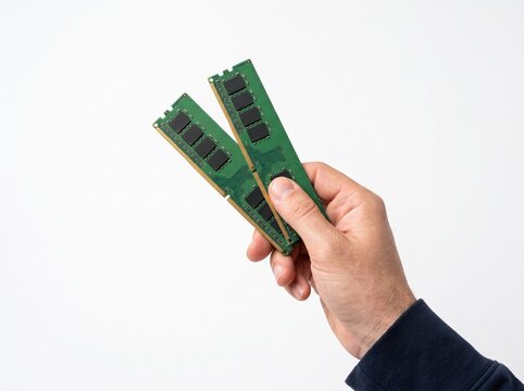 Two Computer RAM Modules in Hand: A close-up shot features a hand holding two green computer RAM modules, highlighting the components of digital technology.