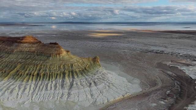 Aerial view of the dramatic limestone formations of Bozjyra in the desert landscape, with textured cliffs and vast salt flats under a cloudy sky in Aktau, Mangystau Region, Kazakhstan.