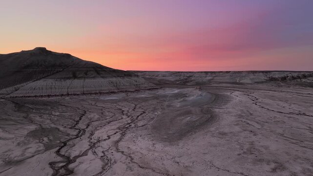 Aerial view of Gora Bokty with its unique layered geological formations under a vibrant sunset sky in Karakiya District, Mangystau Region, Kazakhstan.