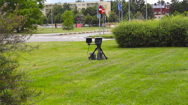 Mobile police Lidar speed camera system on a tripod monitoring city traffic for law enforcement purposes, measuring vehicle velocity to enforce speed limits and improve road safety