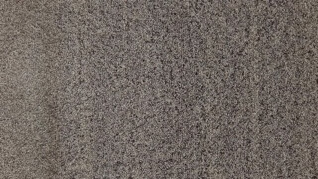 A top-down view of a dense, mottled carpet texture providing a neutral background for modern interior design and architectural projects.