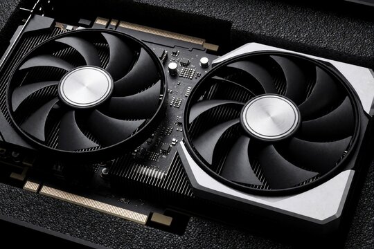 Modern graphics card close up view shows dual cooling fans, metallic heatsink inside pc tower case. Powerful hardware component for high performance gaming computer systems provides fast data