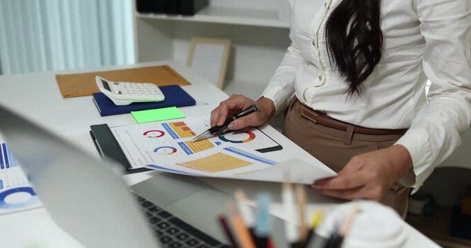 Business professional reviewing financial reports, analyzing business performance, calculating budgets and managing office documents with digital devices for accounting, finance and corporate planning