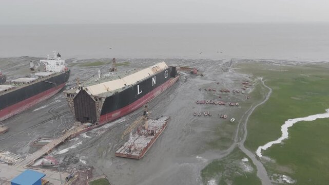 Aerial view of the Ship Breaking Yard Chittagong with large cargo ships and an LNG tanker beached on the mudflats for dismantling in Bhatiari, Chittagong Division, Bangladesh.