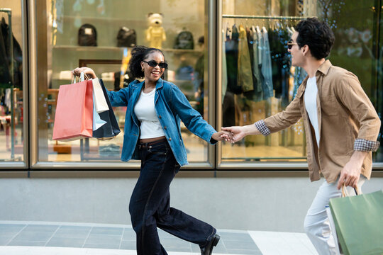 Latino man and Black woman standing outdoors while shopping in city. 